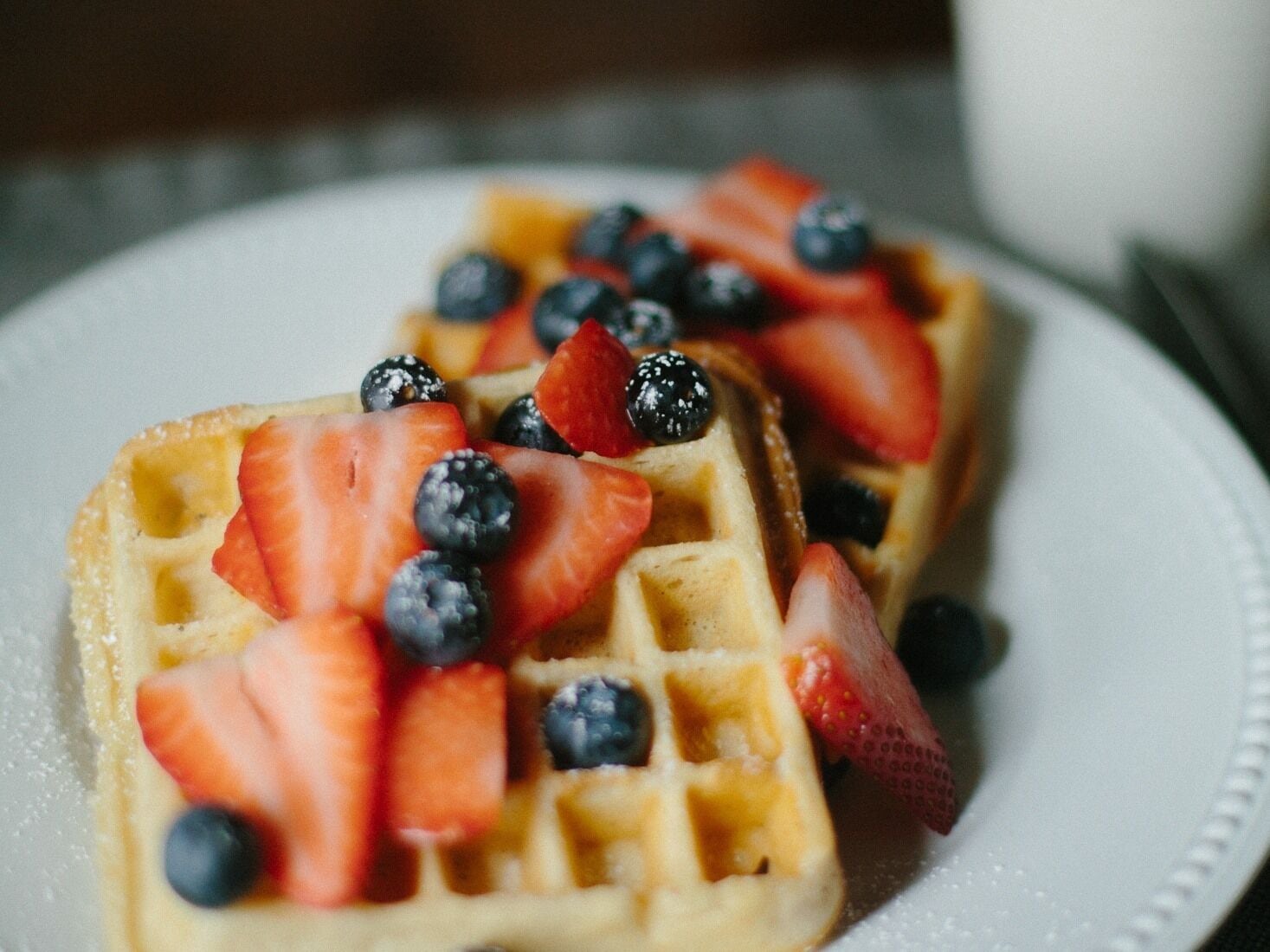 Twee wafelplaten belegd met aardbeien en blauwe bessen.