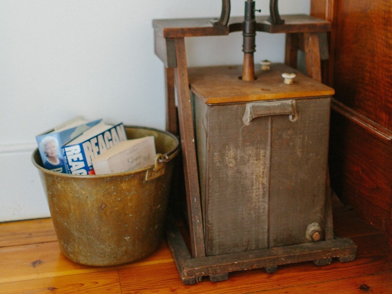 A vintage printing press next to a metal bucket filled with printed materials.