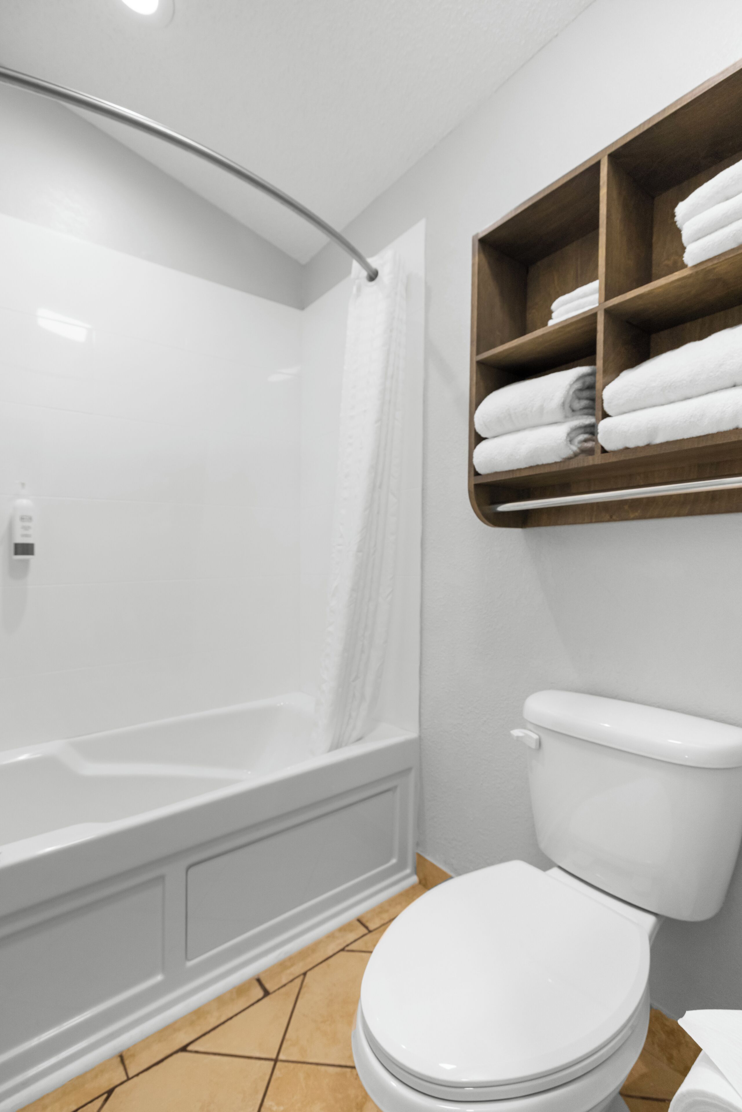 Une salle de bain avec une baignoire, des toilettes et une étagère avec des serviettes.