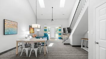 A modern interior with a dining area, staircase, and artwork on the walls.