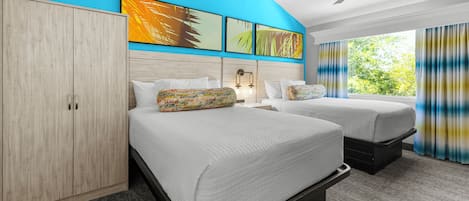 A hotel room with two beds, a wardrobe, a ceiling fan, and artwork on the wall.
