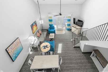 Un interior moderno con comedor, sofá, televisor y escalera.