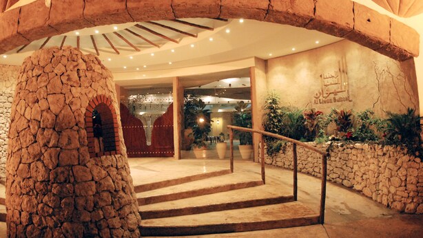 A stone archway leading to a staircase with a metal railing. - Al Liwan Suites (Doha)