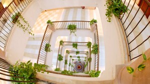 A spiral staircase with a checkered floor pattern and potted plants on the railings. - Al Liwan Suites (Doha)