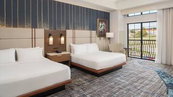 A hotel room with two beds, a large window with a view, a patterned carpet, and a painting on the wall.