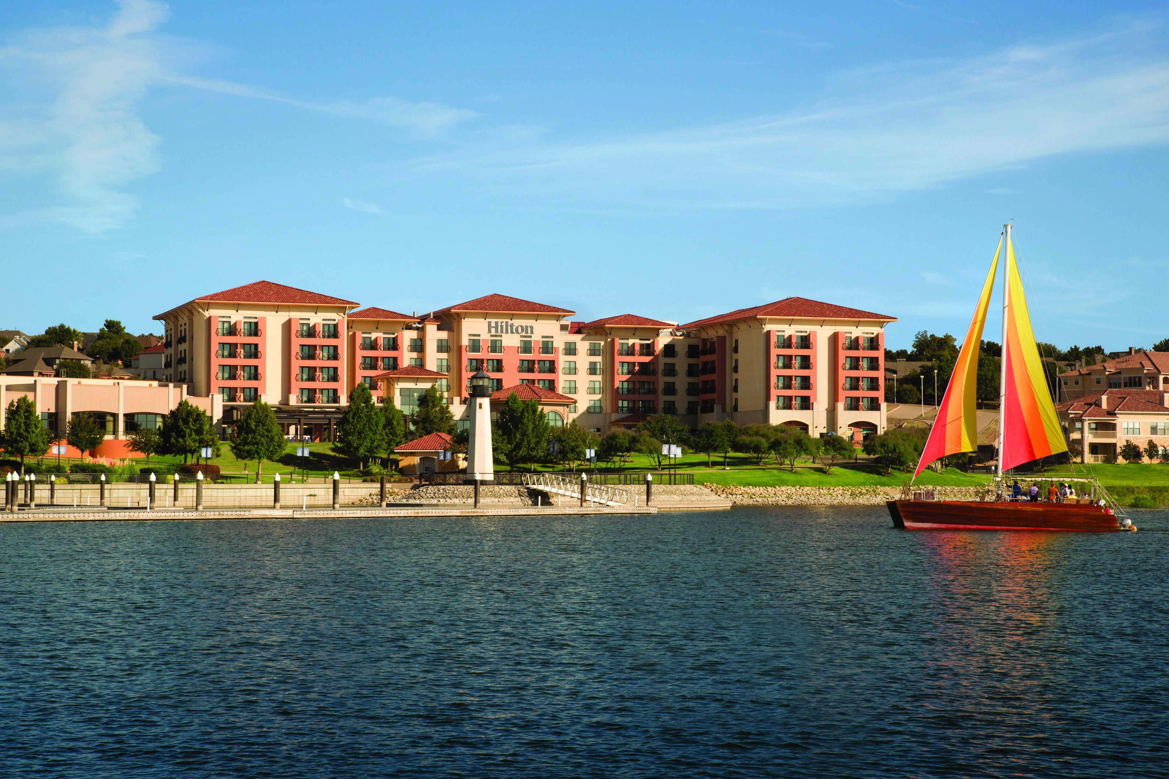A hotel with multiple buildings, a waterfront, and a sailboat.