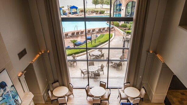 A spacious lounge area with a large window overlooking a pool and outdoor seating.