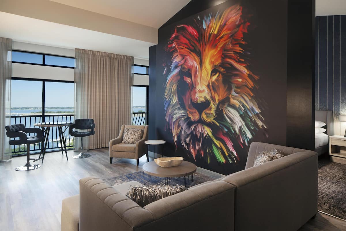 A modern living room with a large window, a sofa, a coffee table, and a painting of a lion.