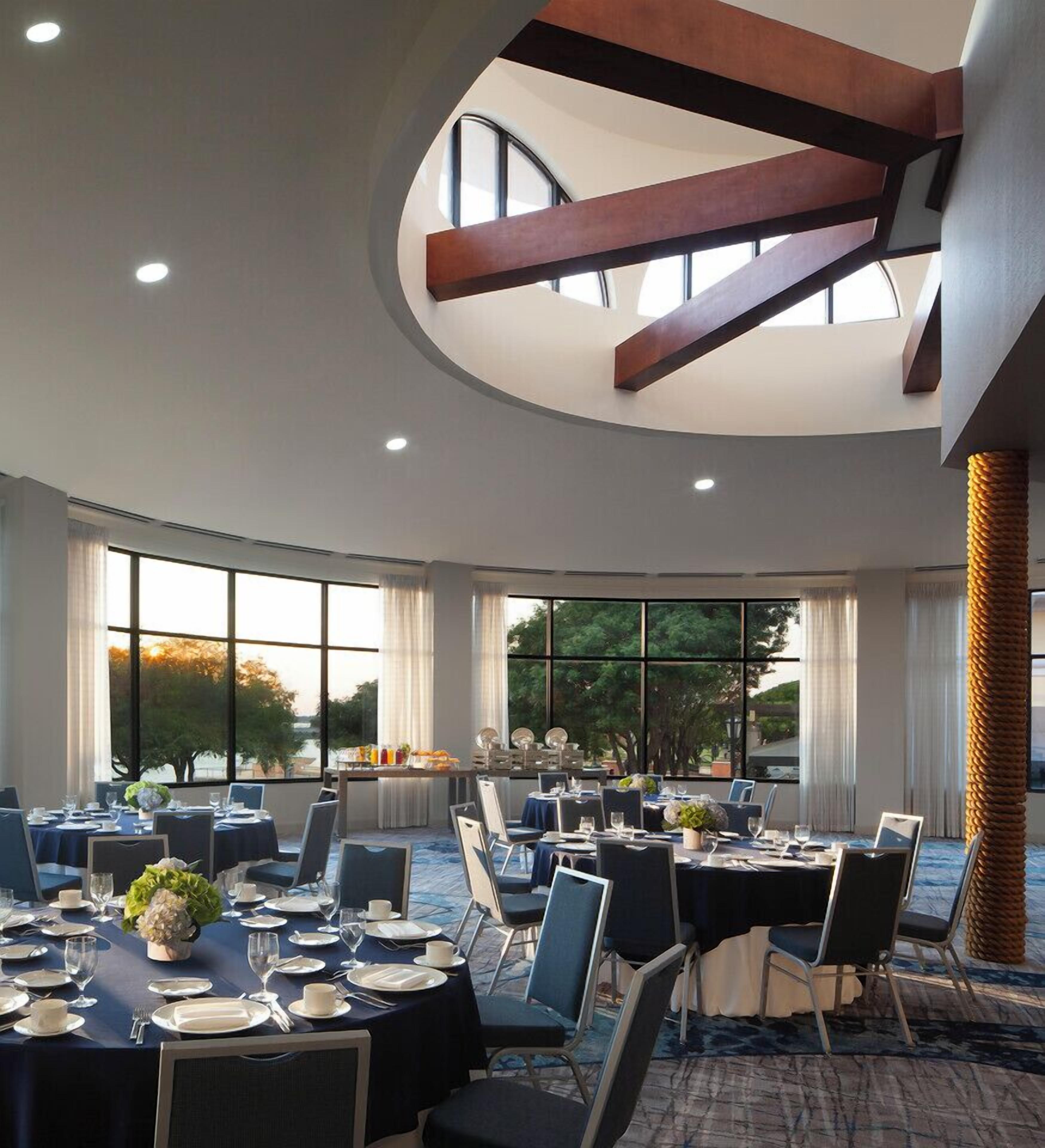 A conference room with round tables, chairs, and a high ceiling with exposed beams.