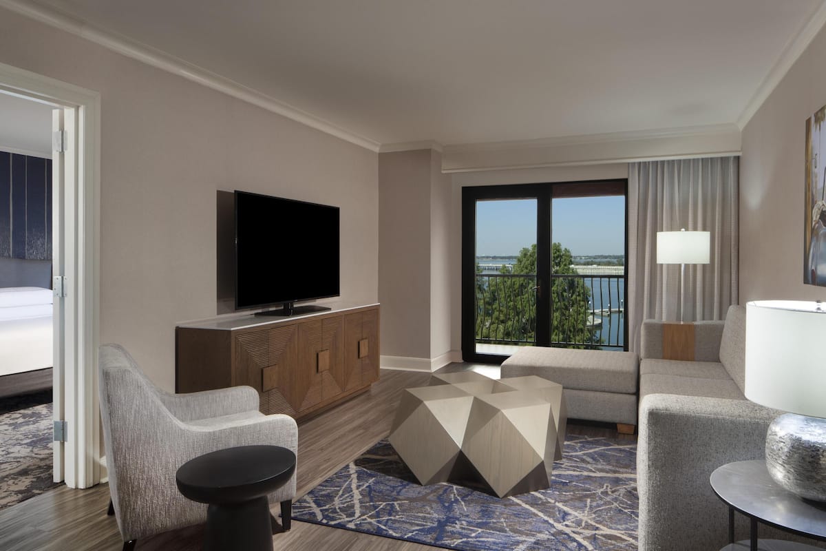 A hotel room with a bed, a TV, a sofa, a coffee table, and a view of the outdoors.