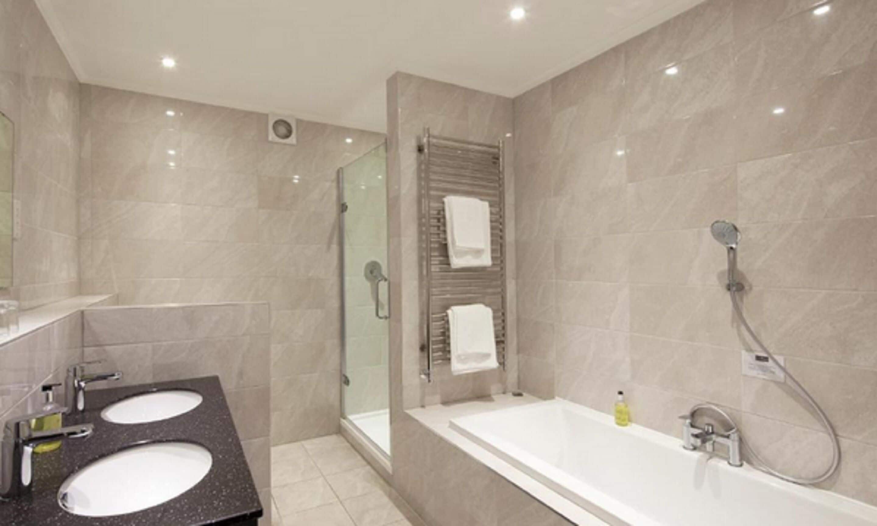A modern bathroom with two sinks, a shower, and a large bathtub.