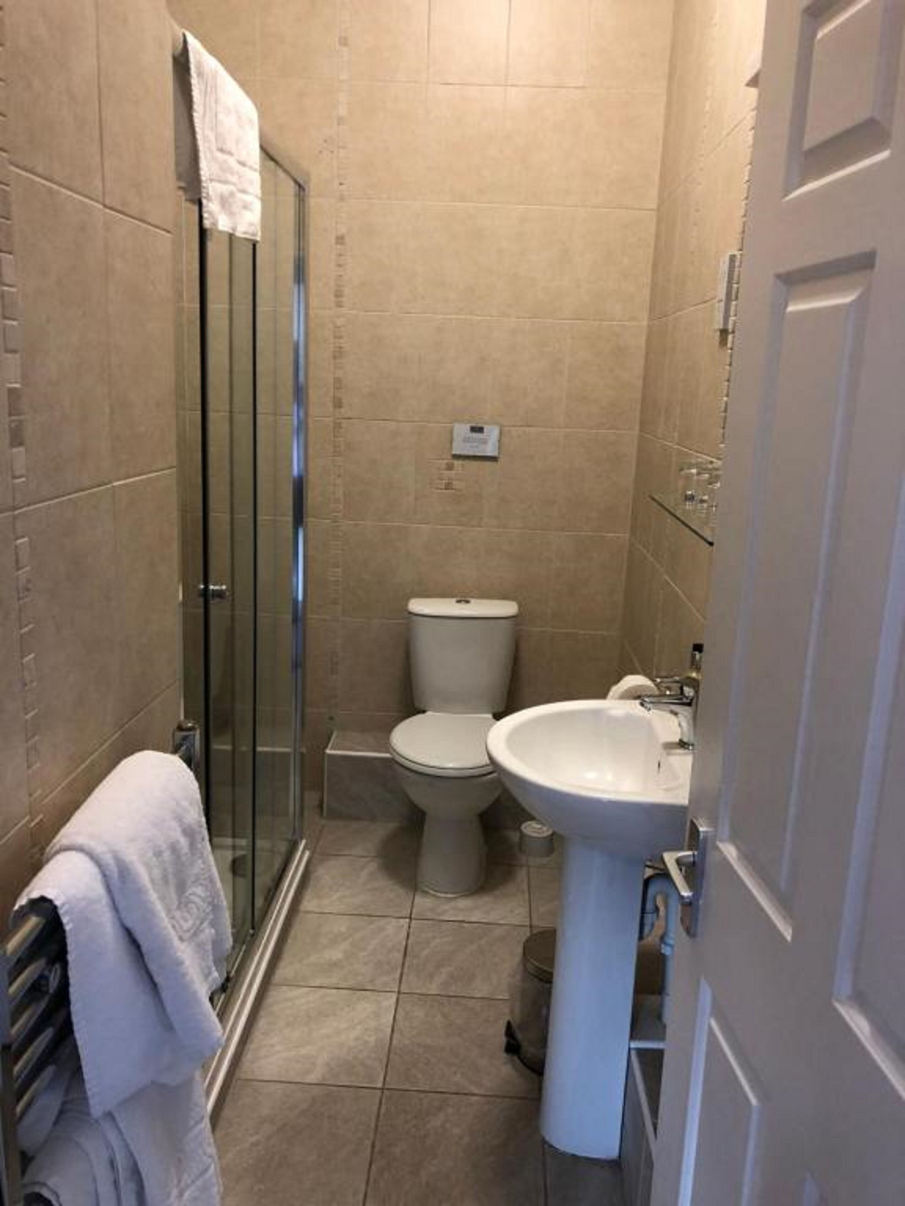 A compact bathroom with a glass shower enclosure, a toilet, and a sink.