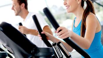 Ein Fitnessstudio mit Ergometer und einer trainierenden Frau und einem Mann.