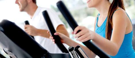 Un gimnasio con bicicletas estáticas y un hombre y una mujer haciendo ejercicio.