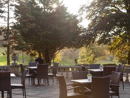 An outdoor patio with wicker furniture and a view of a park.