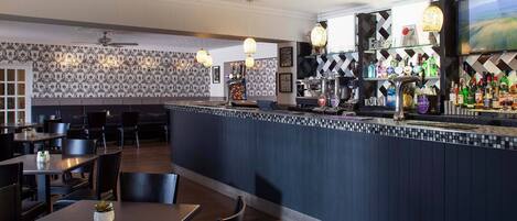 A bar area with a counter, seating, and a decorative wall.