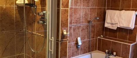 A bathroom with a glass-enclosed shower, a bathtub, and a tiled wall.