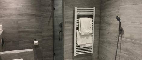 Un baño moderno con cabina de ducha de vidrio, toallero empotrado, bañera y lavabo.