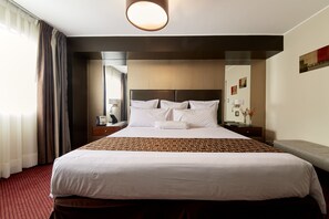 A hotel room with a large bed, a nightstand, a lamp, and a mirror. - Hotel Carrera SAC (Lima)