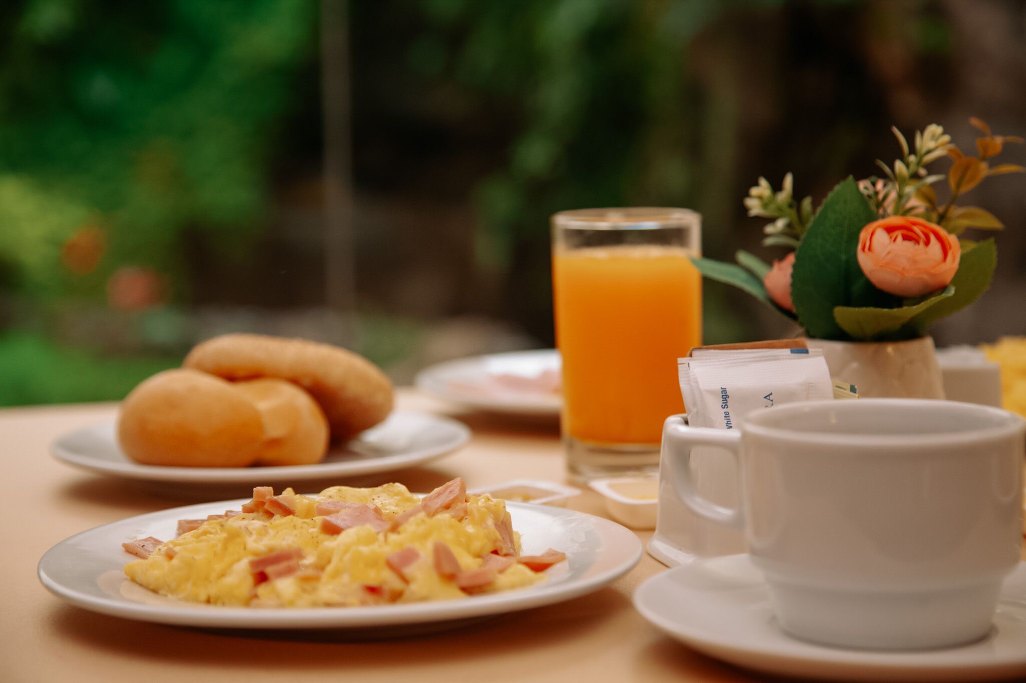 A breakfast setting with plates of food, a glass of orange juice, and a cup.