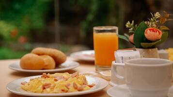 A breakfast setting with plates of food, a glass of orange juice, and a cup.