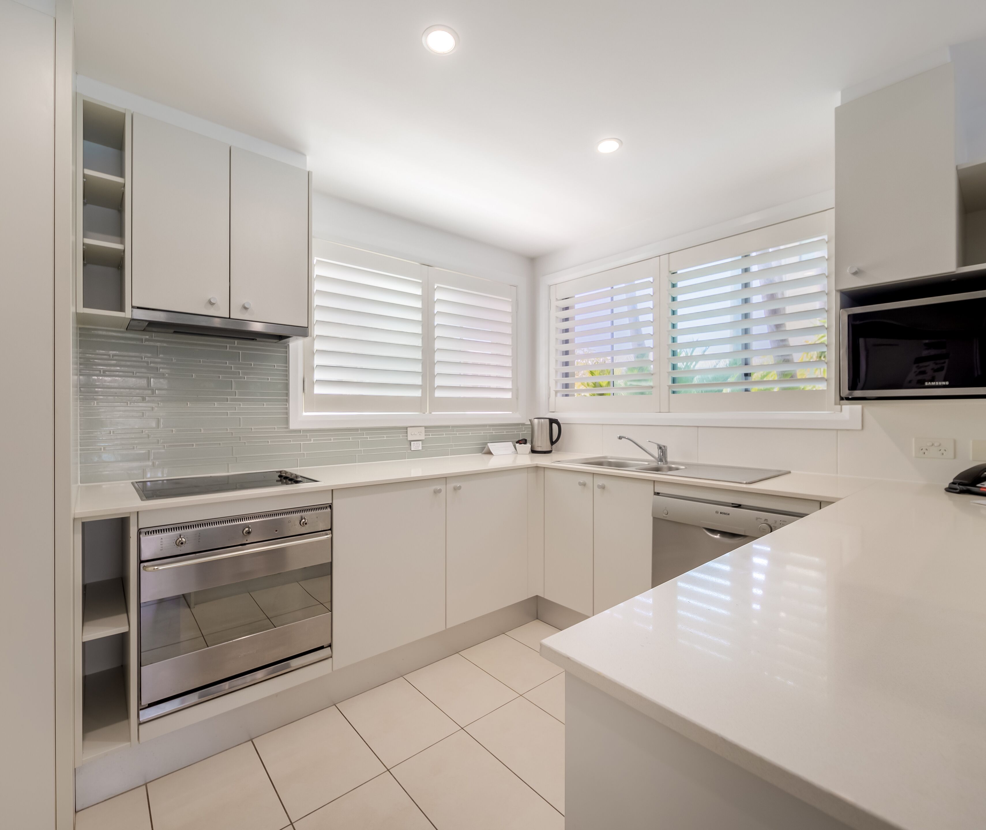 A modern kitchen with white cabinetry, a stainless steel oven, a Bosch dishwasher, and a Samsung microwave.
