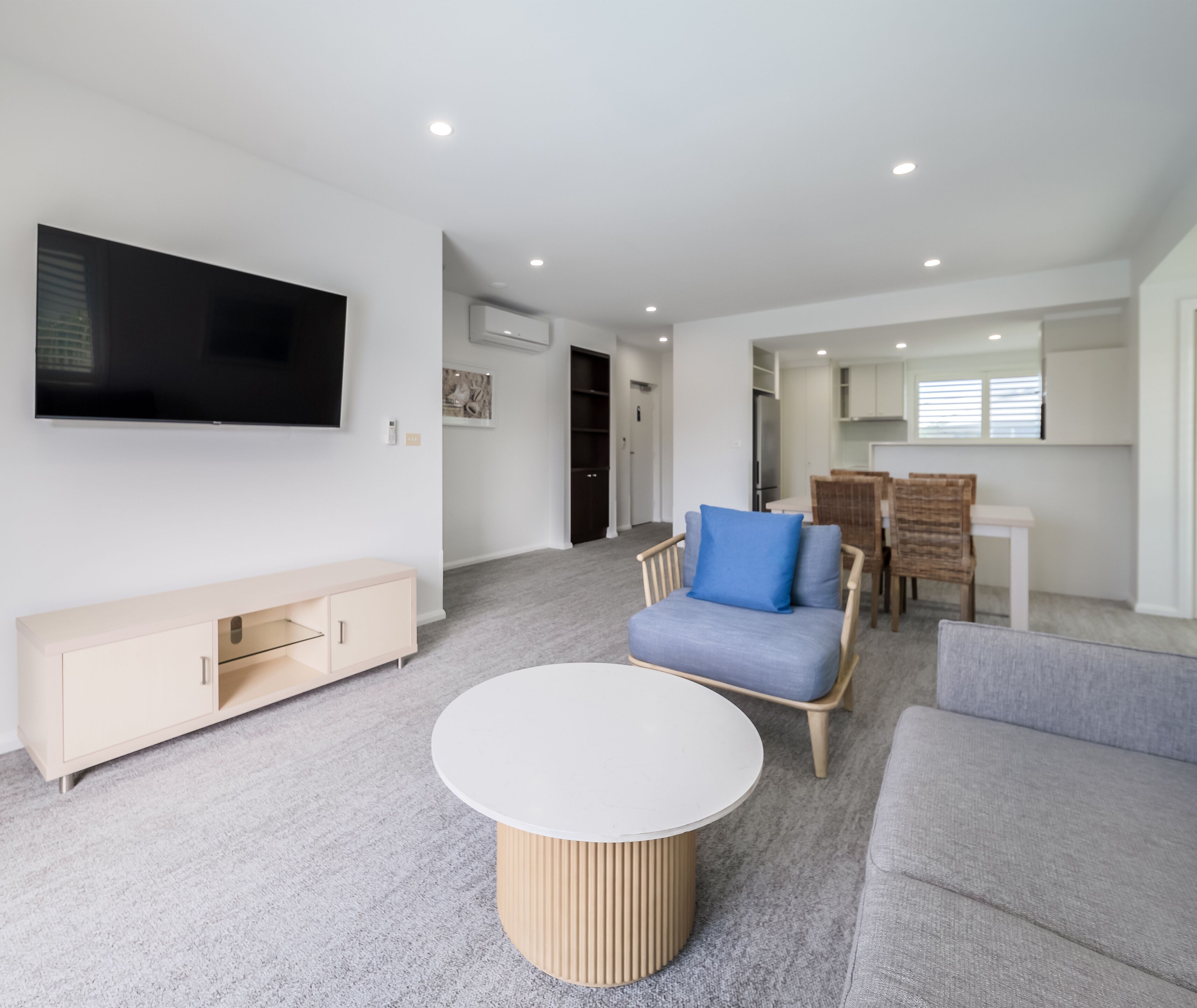Una sala de estar moderna con un televisor de pantalla plana, una mesa de centro redonda y dos sofás.