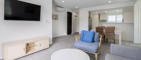 Una sala de estar moderna con un televisor de pantalla plana, una mesa de centro redonda y dos sofás.