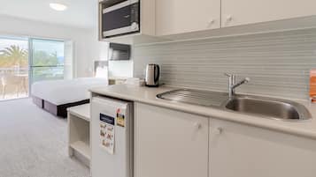 A modern kitchen with a built-in microwave, a kettle, and a sink.