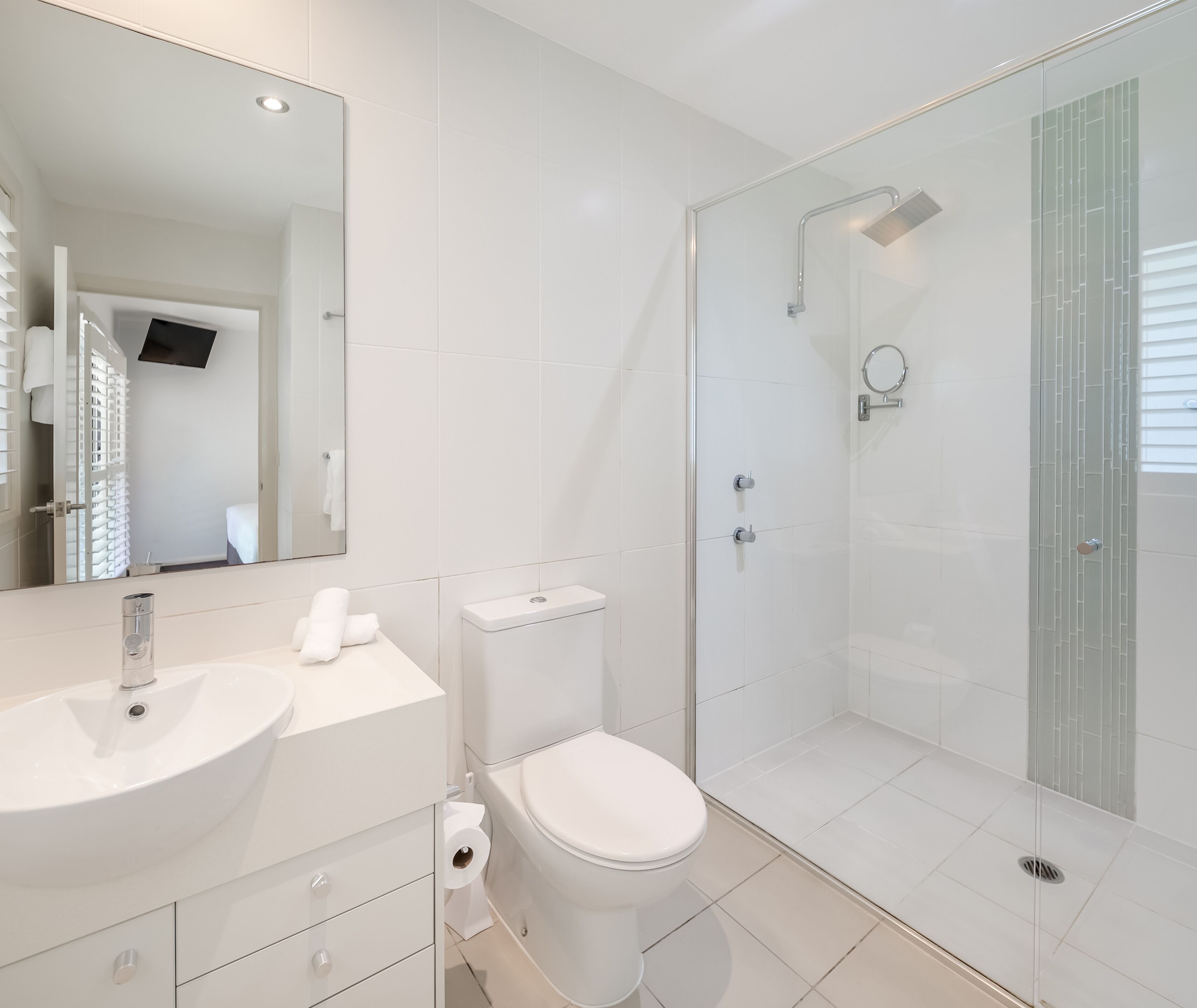 Une salle de bain moderne avec un lavabo blanc, des toilettes et une douche à parois de verre.