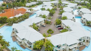 A resort with multiple buildings, a central swimming pool, and surrounding greenery.