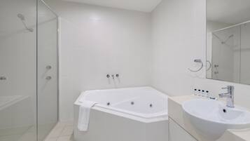 Een moderne badkamer met een douchecabine van glas, een vrijstaand bad en een wastafelmeubel met een wastafel.