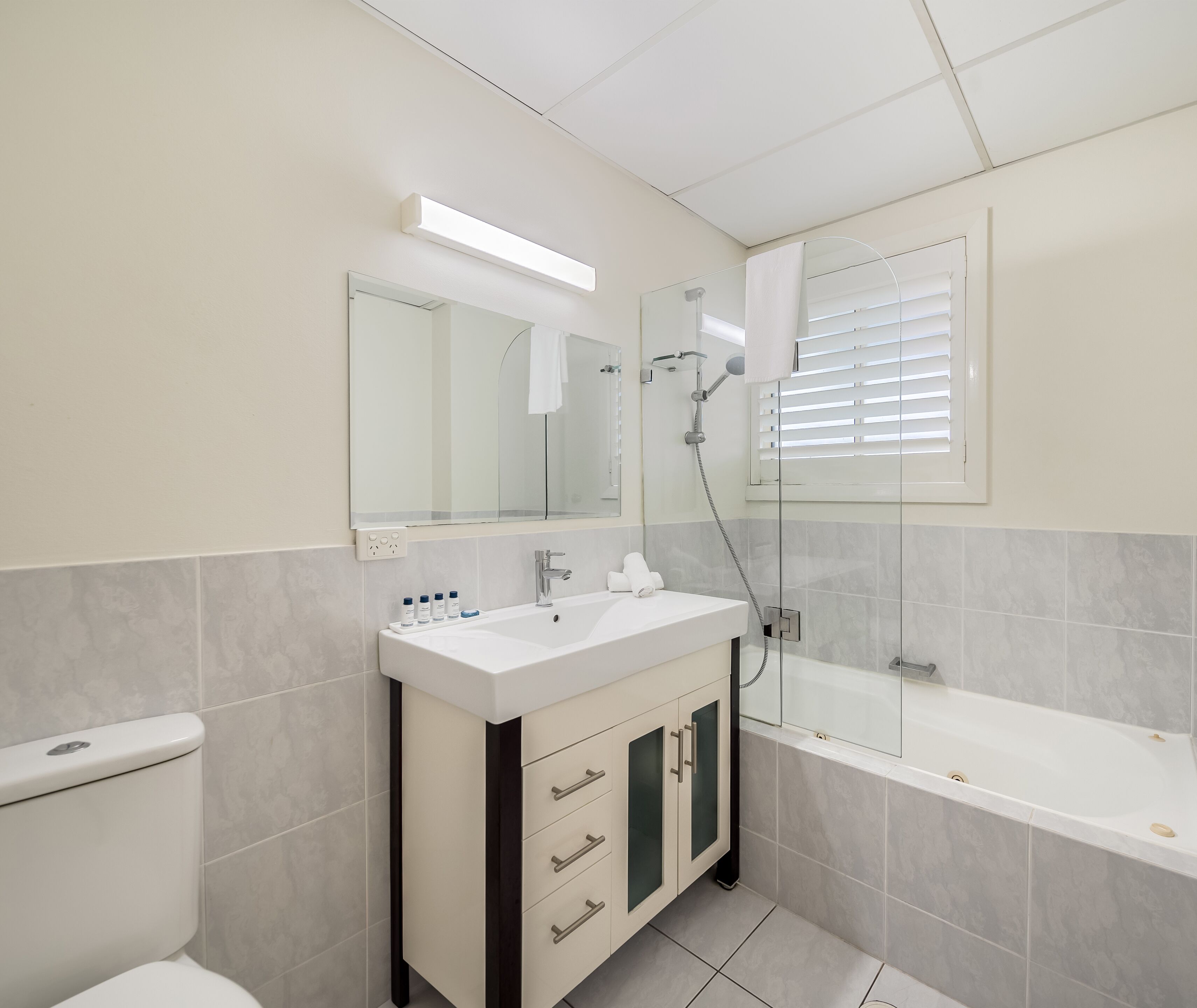 A modern bathroom with a toilet, sink, vanity, and bathtub.