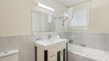A modern bathroom with a toilet, sink, vanity, and bathtub.