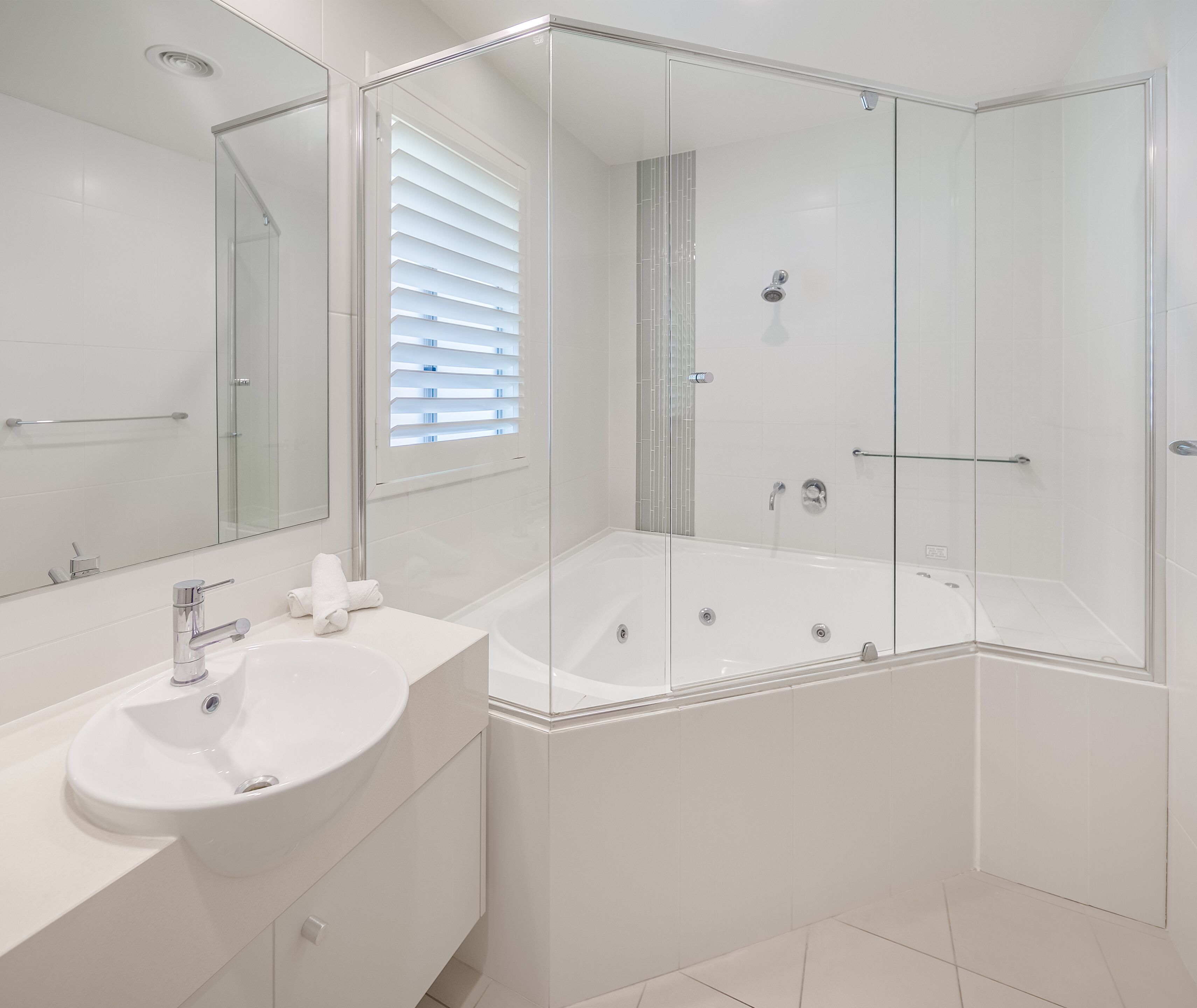 Une salle de bain moderne avec une douche à parois de verre, un lavabo blanc et un grand miroir.