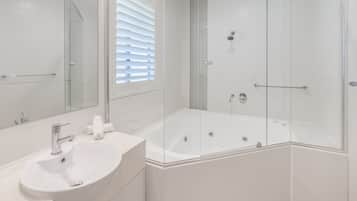 Une salle de bain moderne avec une douche à parois de verre, un lavabo blanc et un grand miroir.