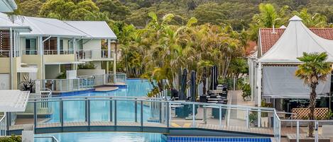 A swimming pool area with a view of a forested hill in the background.