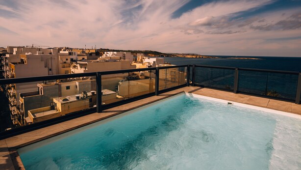 A rooftop pool with a view of the sea and buildings. - Hotel Primera (St. Paul's Bay)