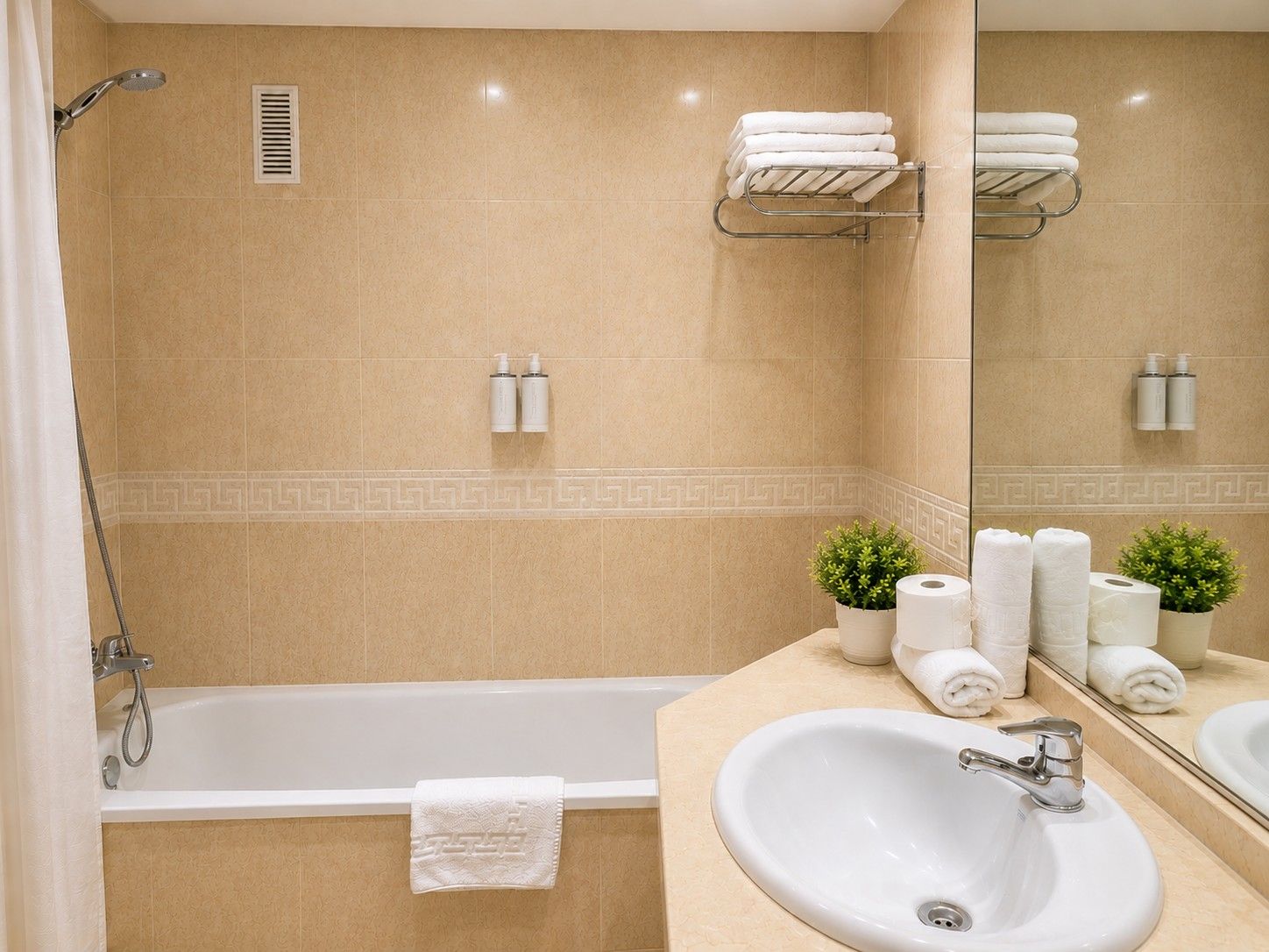 Un baño con bañera, lavabo, espejo, toallas y artículos de aseo.