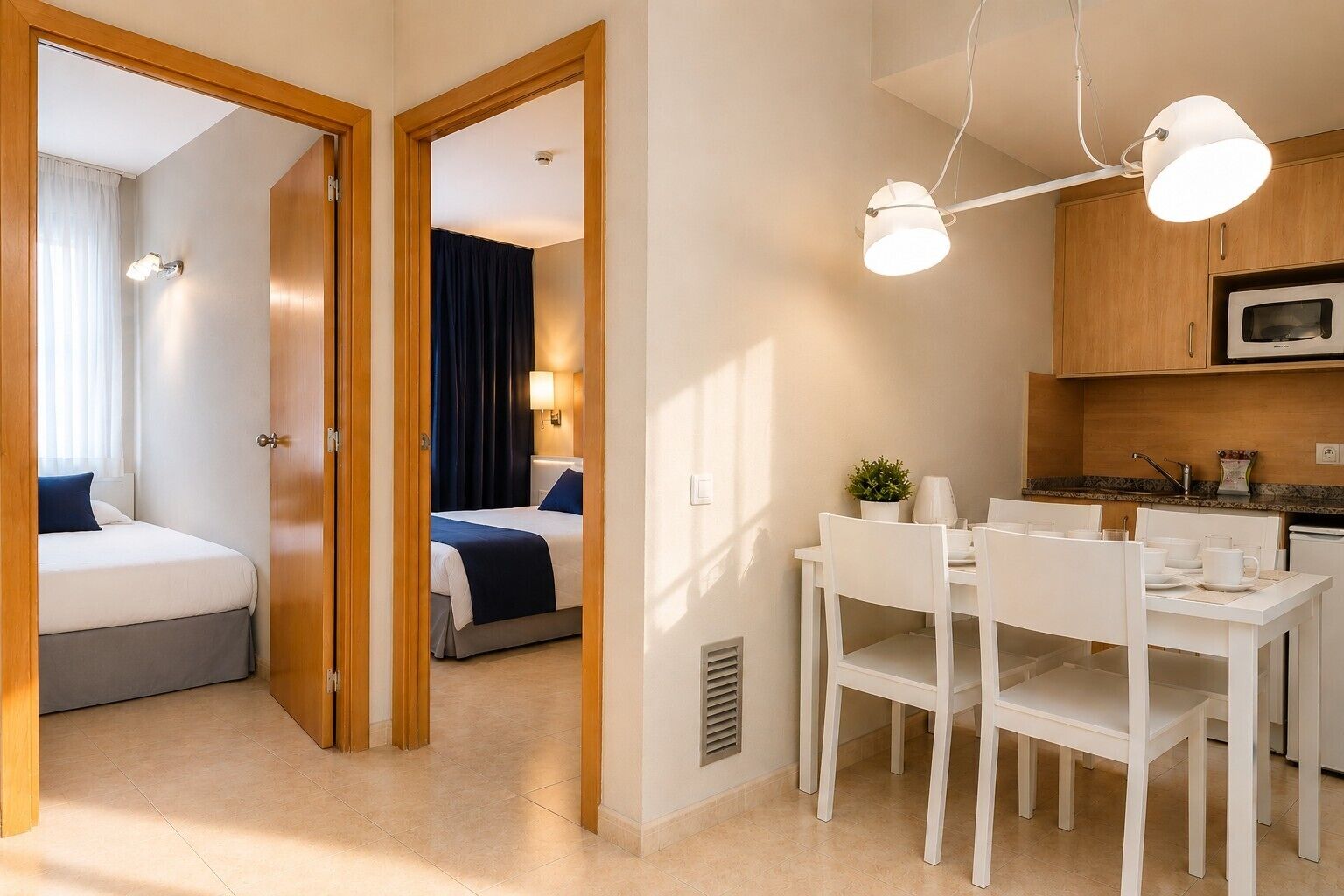 Une chambre d’hôtel comprenant un lit, un coin repas avec une table et des chaises, et un coin cuisine équipé d’un four à micro-ondes.