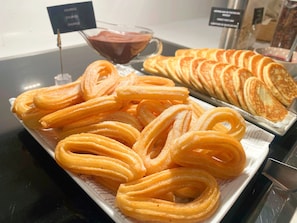 Churros auf einem Teller, eine Schale Schokoladensauce und eine Platte Pfannkuchen.