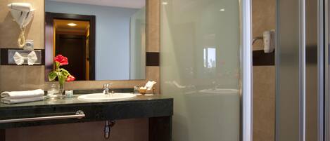 A modern bathroom with a glass-enclosed shower, a sink with a towel rack, and a mirror above the sink.