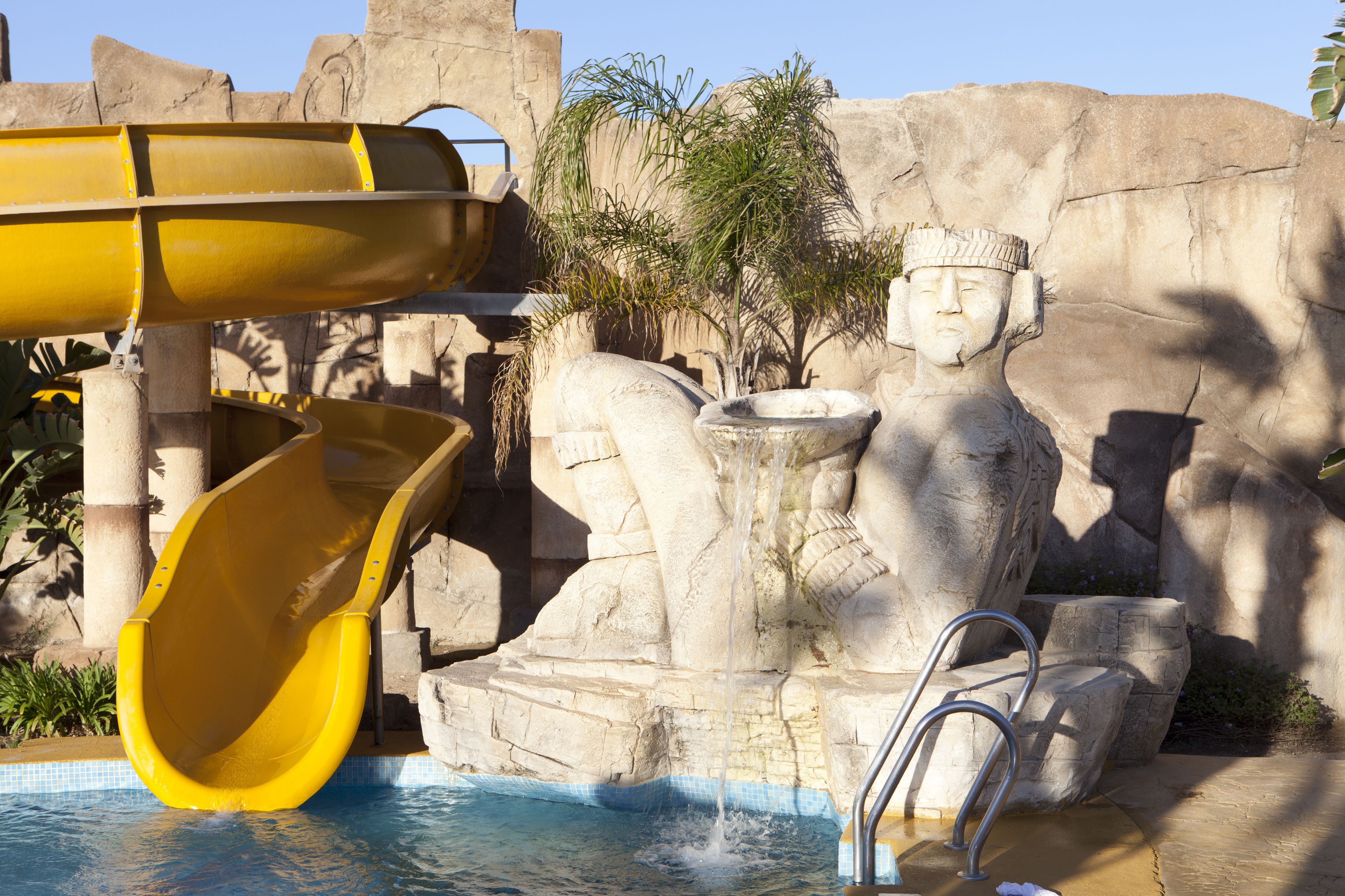 Un tobogan aquàtic, una estàtua i una piscina.