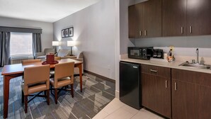 Habitación de hotel compacta con comedor, kitchenette y vistas al exterior.