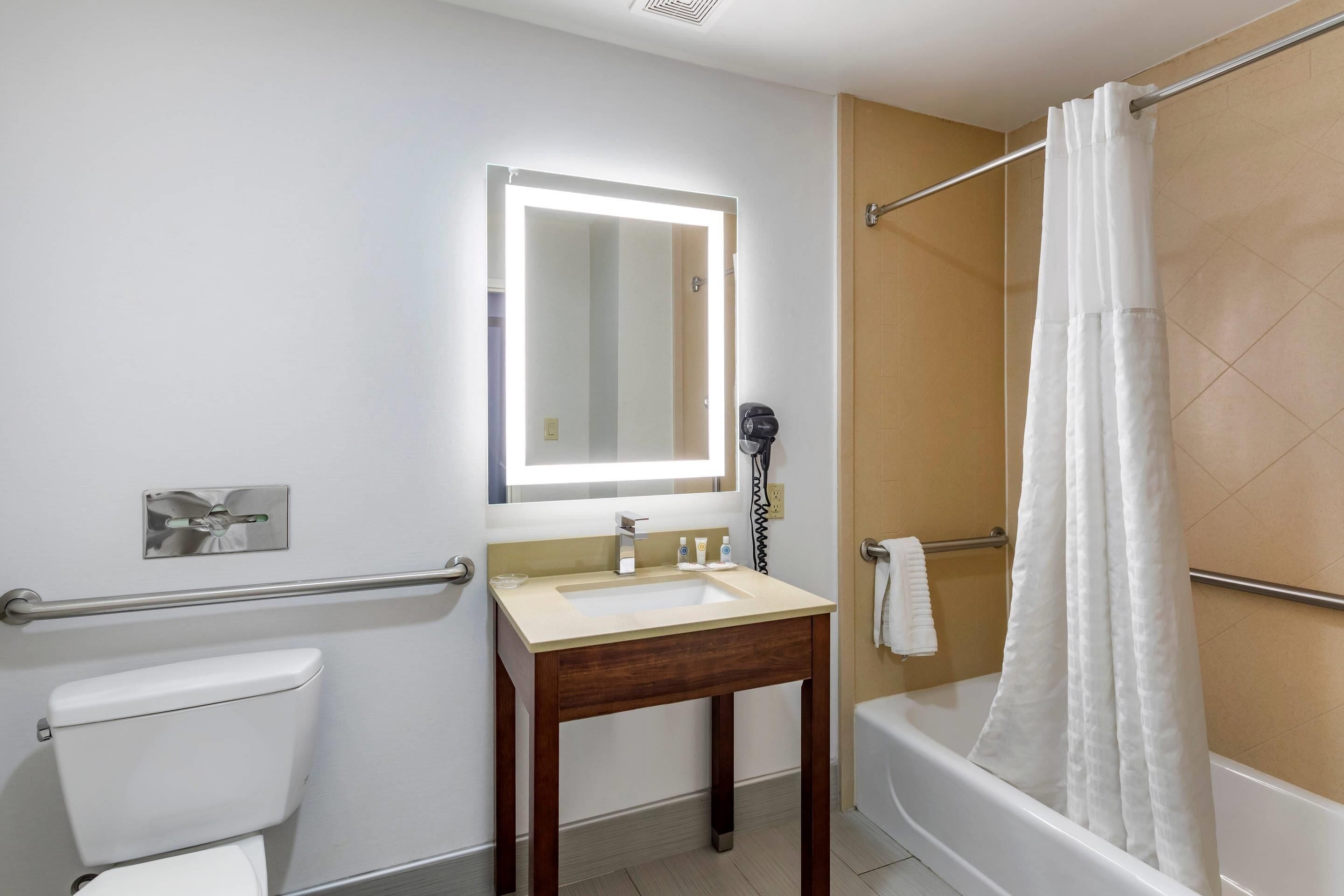 Une salle de bain comprenant des toilettes, un lavabo, un miroir, une douche et un porte-serviettes.