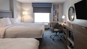A hotel room with two beds, a desk, a chair, a TV, and a window with a view.