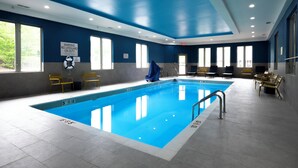 An indoor swimming pool with clear water, surrounded by blue walls and windows.
