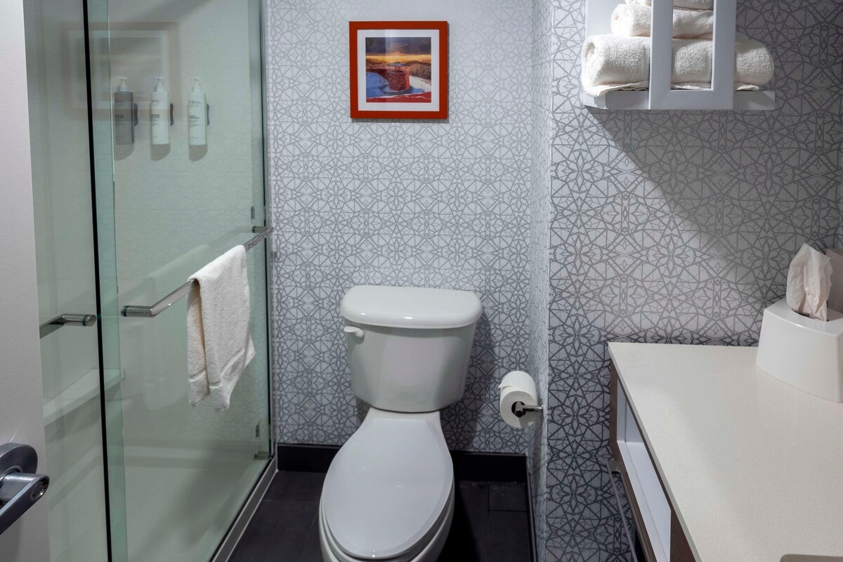 Un baño moderno con cabina de ducha de vidrio, inodoro y zona de lavamanos.