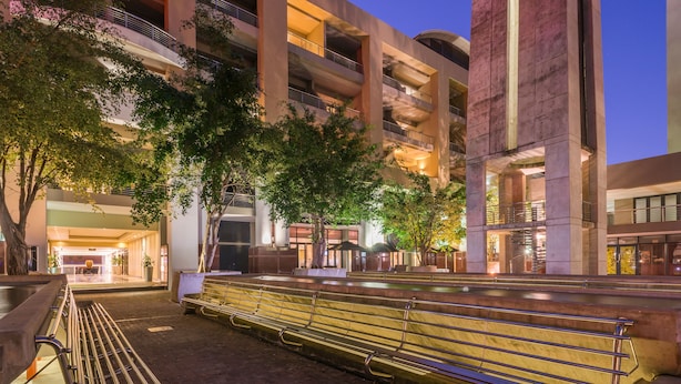 Un bâtiment moderne doté de nombreux balcons et agrémenté d’un élément décoratif aquatique à l’avant.