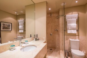 Un baño moderno con un espejo grande, un lavabo, una ducha con cerramiento de vidrio y un inodoro.
